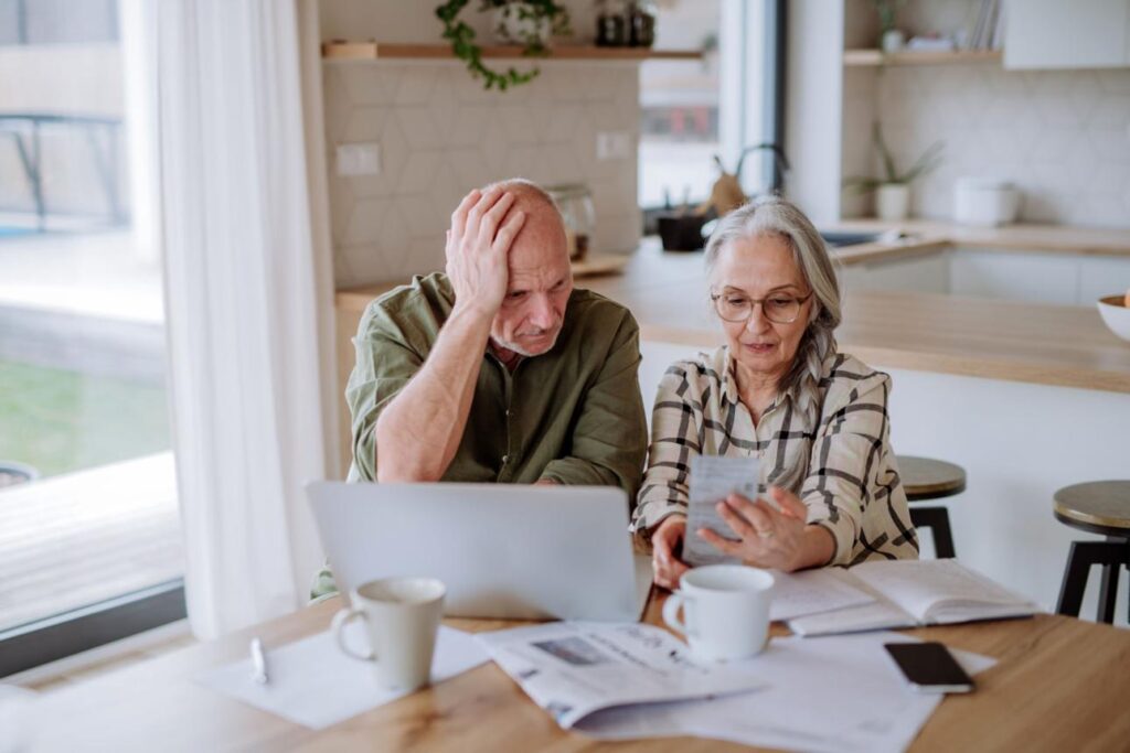 Couple over 50 reviewing monthly expenses and planning smarter spending habits at home