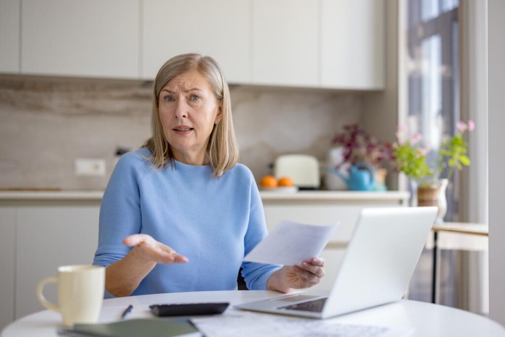 Older adult reviewing household bills and feeling financial stress at home after 50.