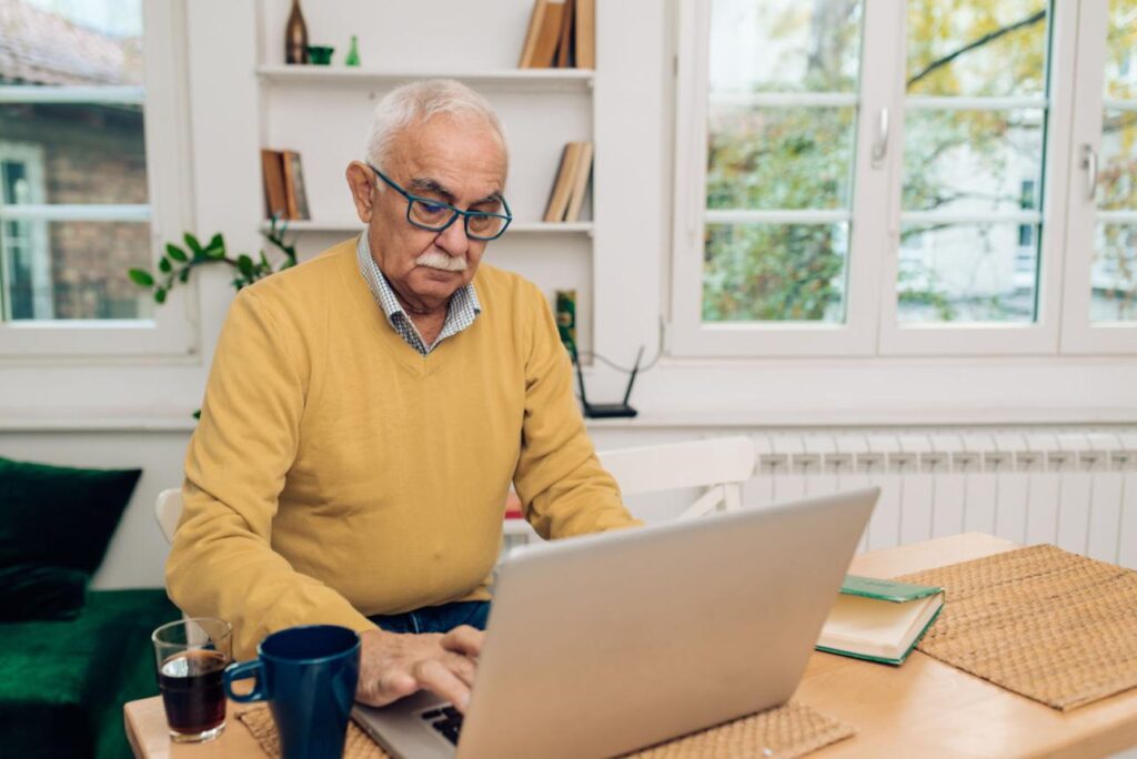 Self-employed adult over 50 organizing business expenses and tax documents at a home office desk