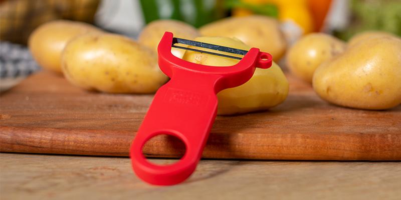 Senior using an ergonomic vegetable peeler in a bright kitchen.
