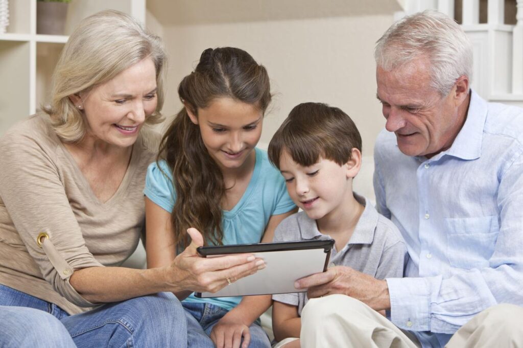 A grandparent and young grandchild sitting together using a tablet while smiling and learning together.
