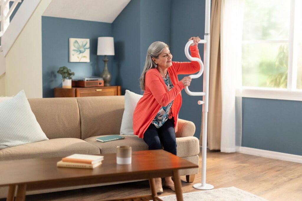 Senior using a transfer pole for support while standing at home