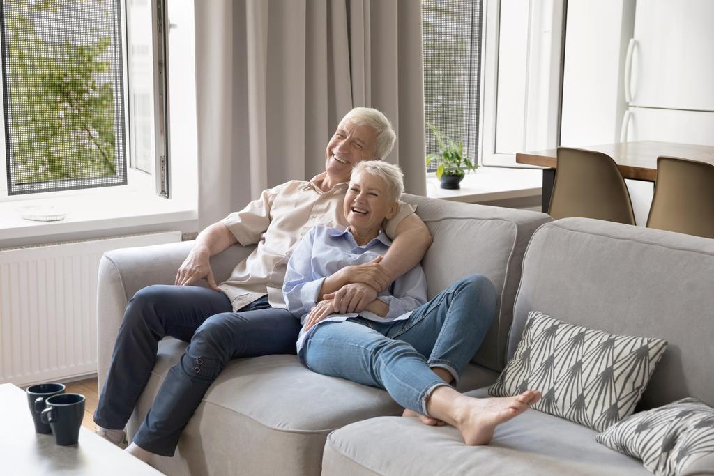 Older adults relaxing on a sofa protected by a modern washable sofa cover.